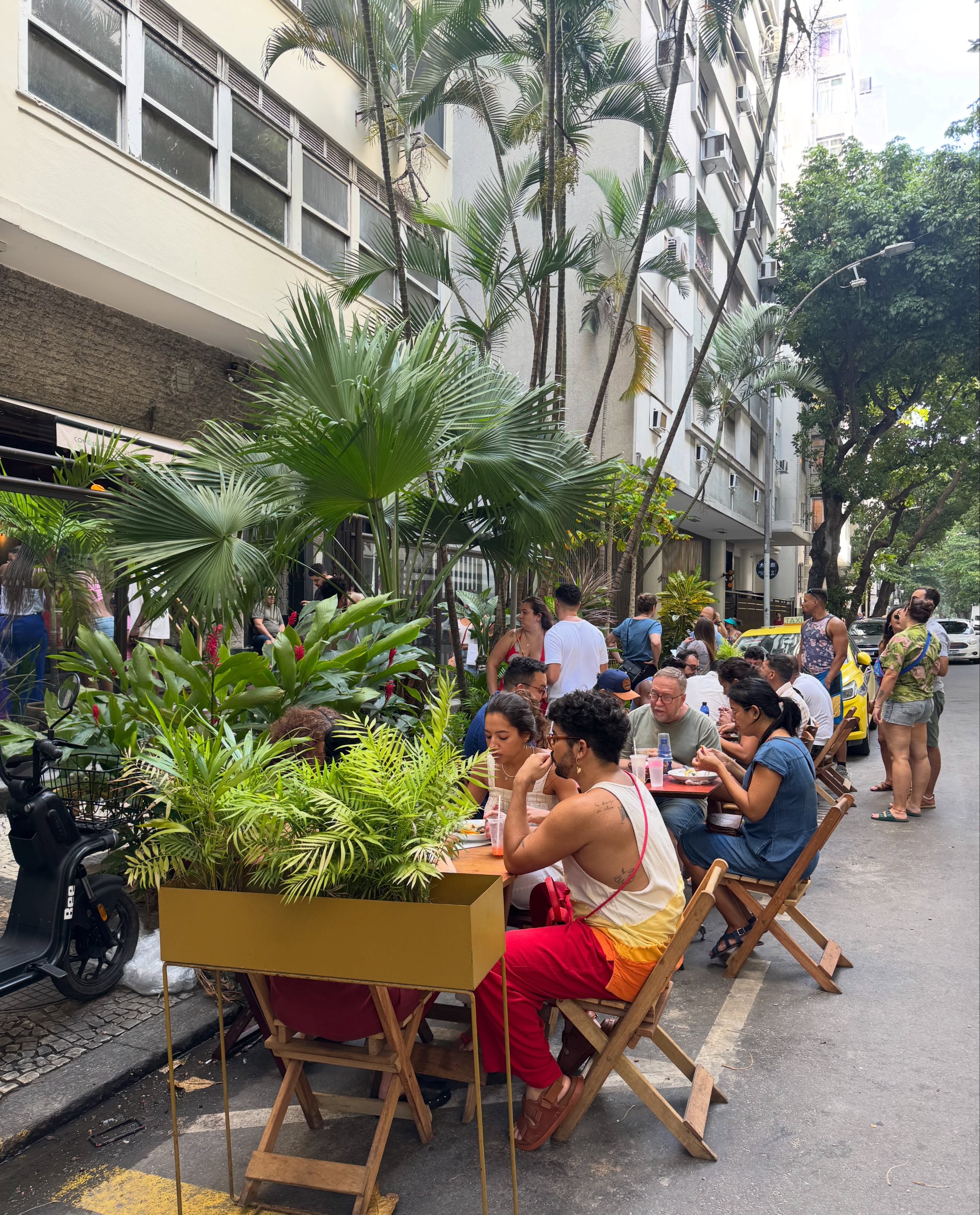 A varanda do Yayá cheia num fim de semana, com as mesas na calçada da Rua Gustavo Sampaio e as palmeiras do Leme